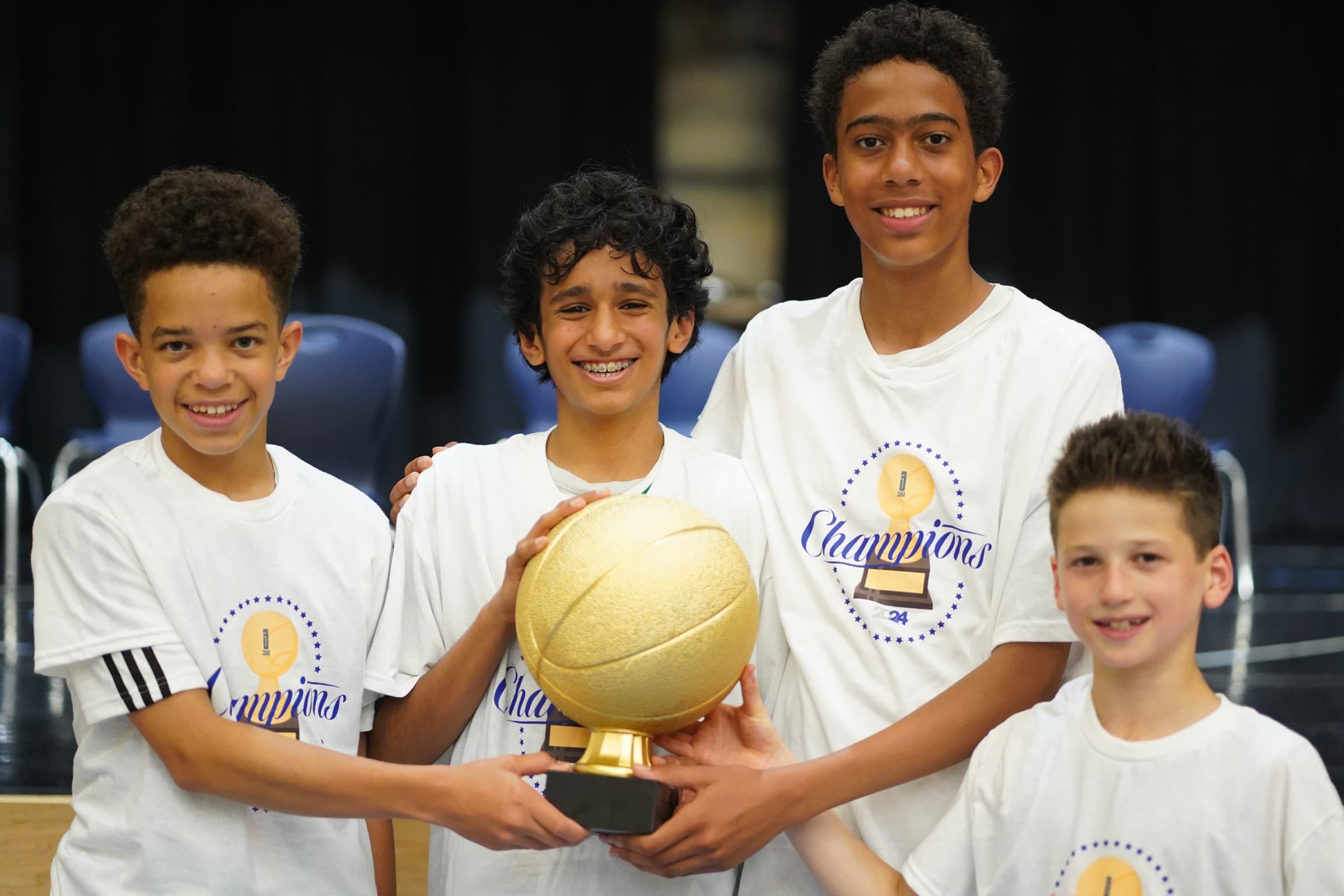 Four league champions holding the golden basketball trophy