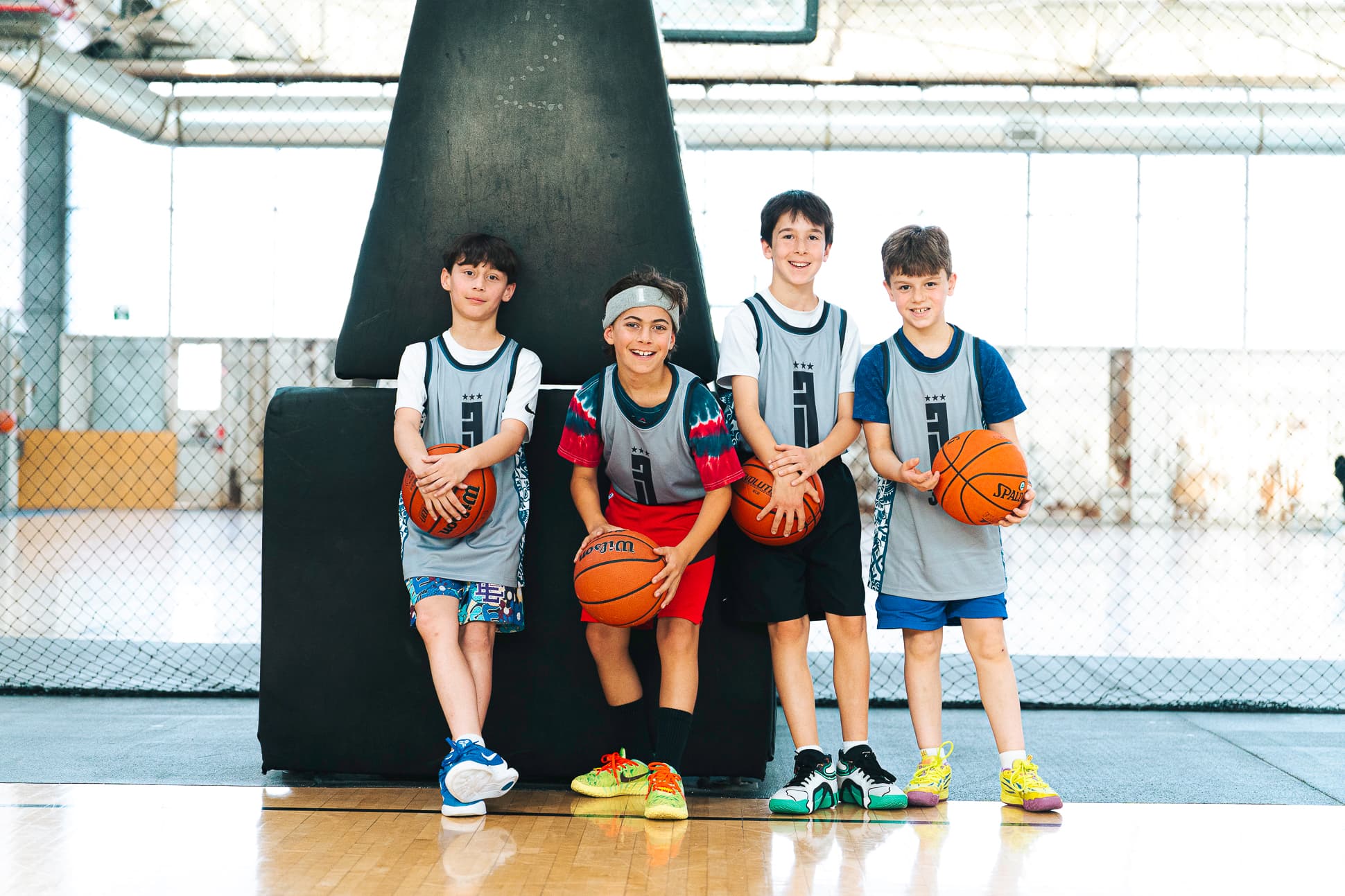 Four 3x3 league players in grey and blue 3BA pinnies posed together with their basketballs